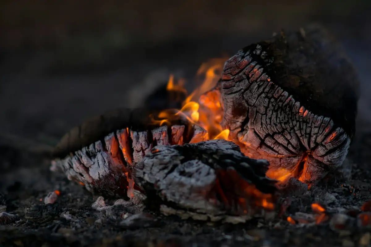 Glowing embers and small flames in a wood fire